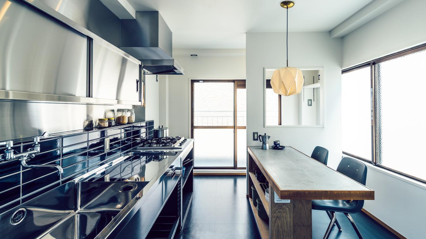 キッチンカウンターは造作、業務用のステンレスキッチンですっきりとした仕上げを採用。開口の奥は洗濯スペースになっています