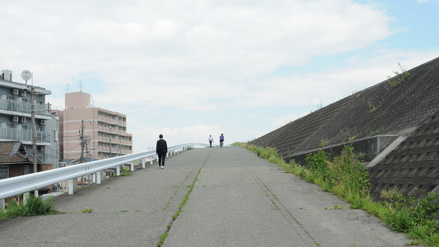 東口から淀川へと続く道のり。平日も河原へ向かう人々の姿が
