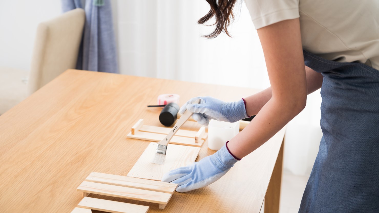 木材にペンキを塗る女性