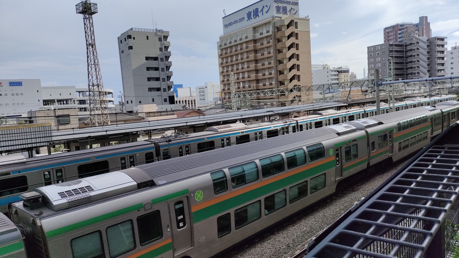 新子安駅に停車中の京浜東北線（奥）と、通過する東海道線（手前）