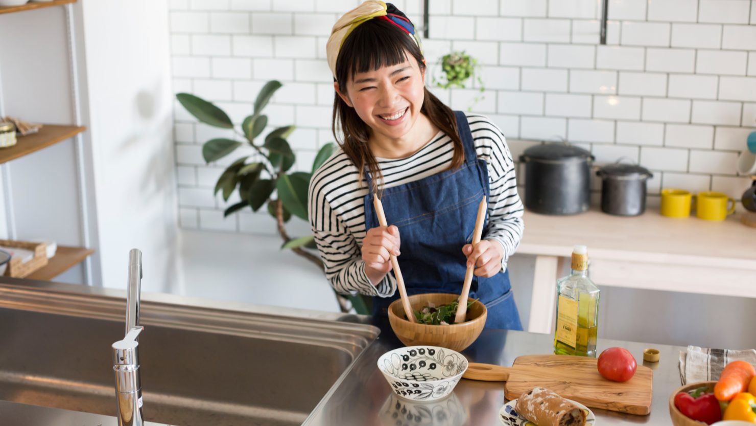 キッチンでオリーブオイルを使ったサラダを作る女性