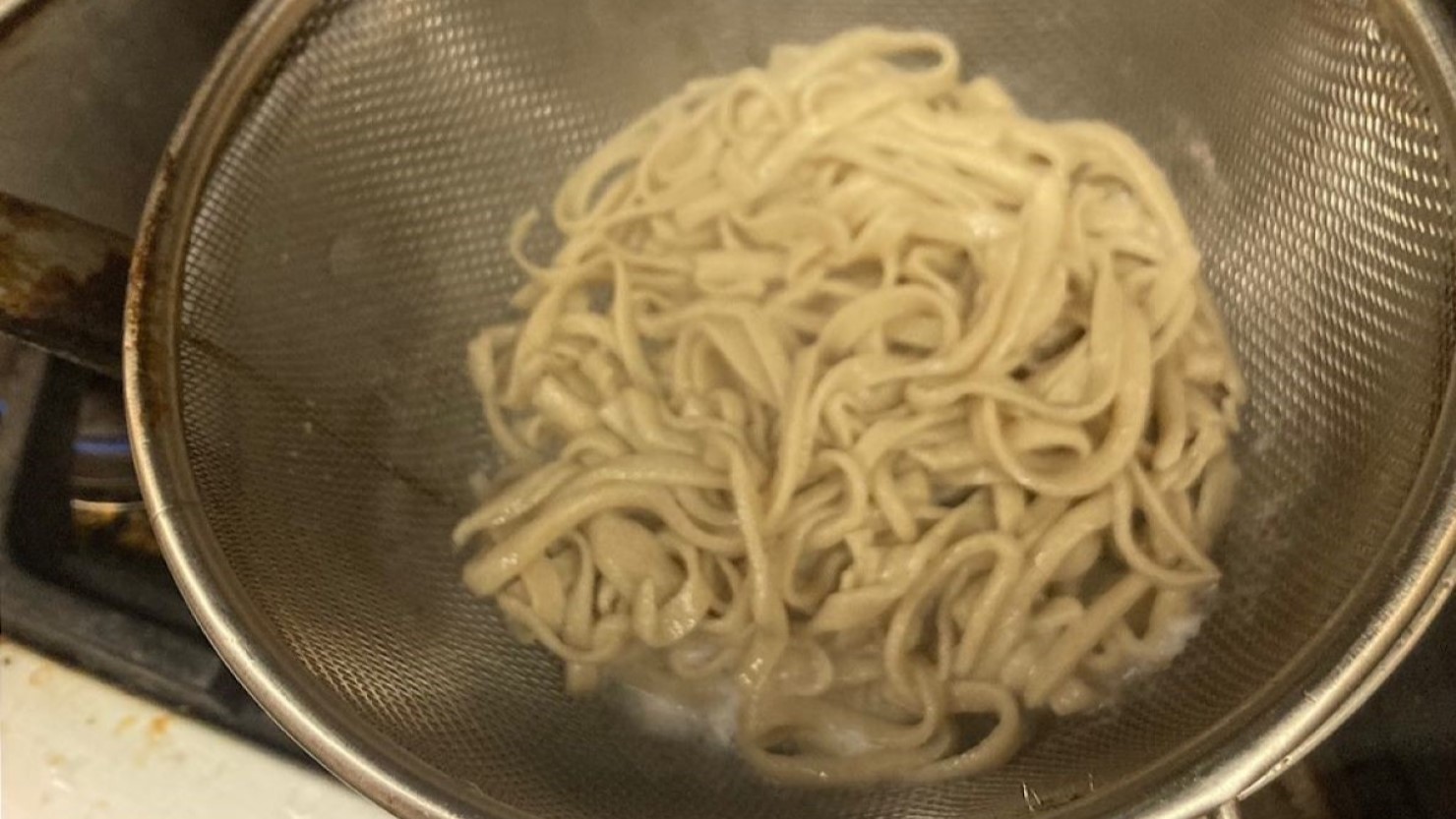 流水で蕎麦をしめる様子