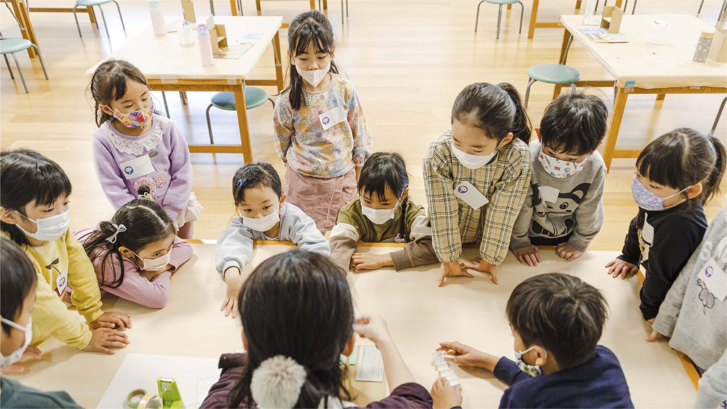 「わたしのお家づくり」の講座の様子。講師を囲んで制作の手順を真剣に聞く子どもたち 　© sato akiko