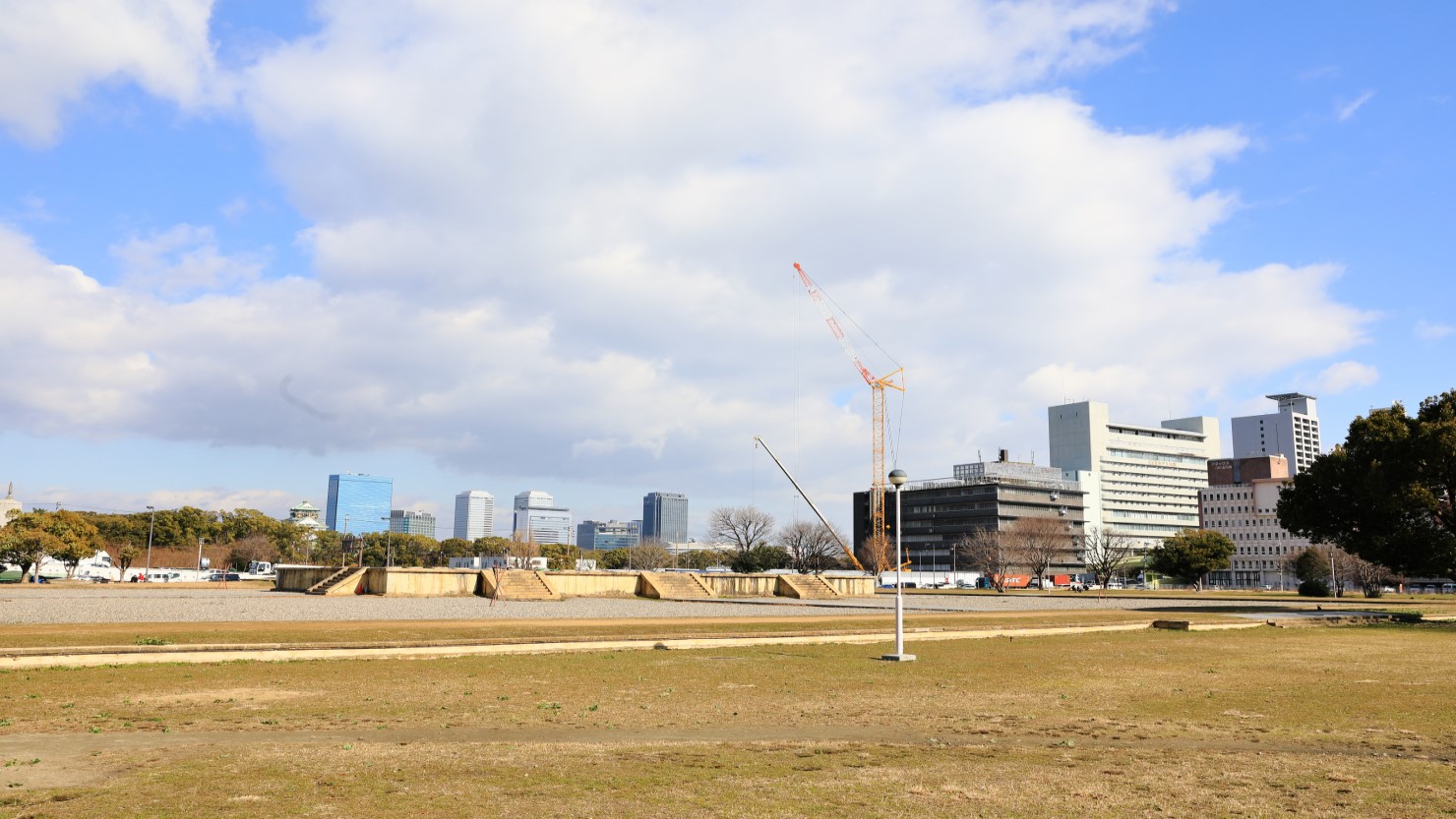 復元された後期難波宮の大極殿基壇。奥には小さく大阪城の姿が。史跡公園には二つの時期の宮殿遺構があることがわかっており、それぞれを前期難波宮、後期難波宮と呼び分けている