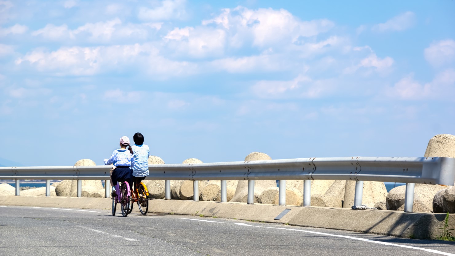 海沿いでサイクリングする夫婦