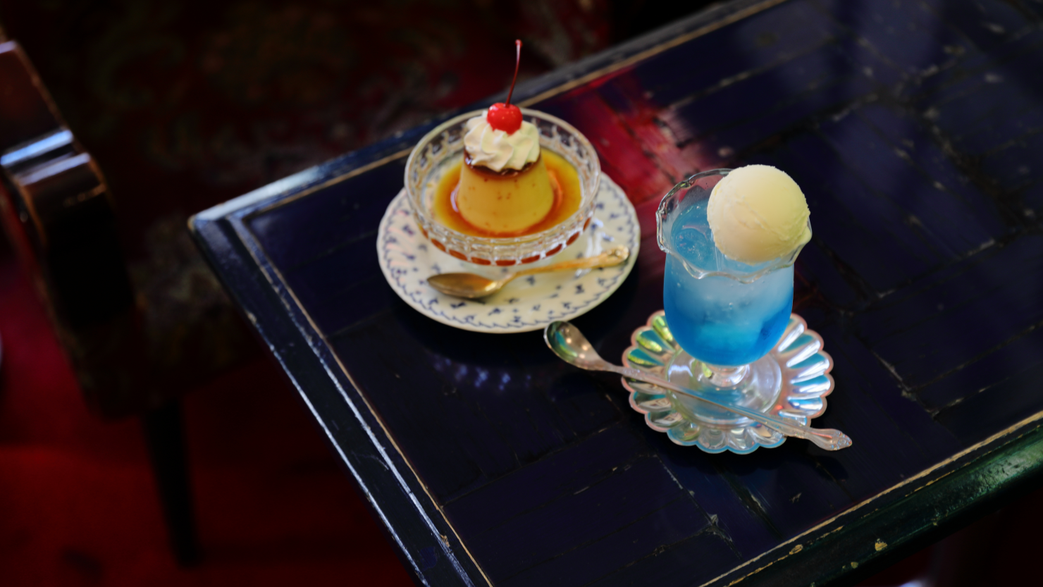 「自家製プリン」（450円）と「クリームソーダ（ブルーハワイ）」（650円）。クリームソーダのグラスも「禁煙室」のもので、カーブを描く縁がかわいい