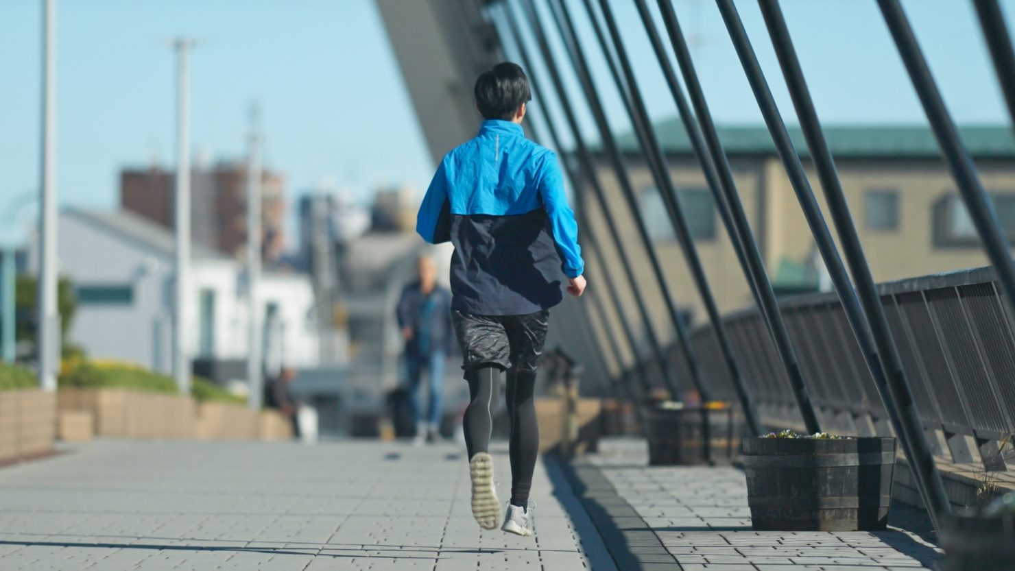 川沿いの遊歩道でジョギングをする男性