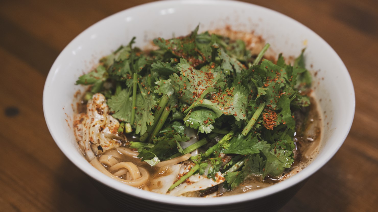 取材当日、即興で作っていただいたラーメン。炒めた玉ねぎとキャベツ、自家製のガラムマサラにラーメンのスープを入れ、麺を加えてパクチーとチリをトッピング。クリスマス仕様の特性ラーメンの出来上がり。朝らぁ麺はこの要領でできあがります