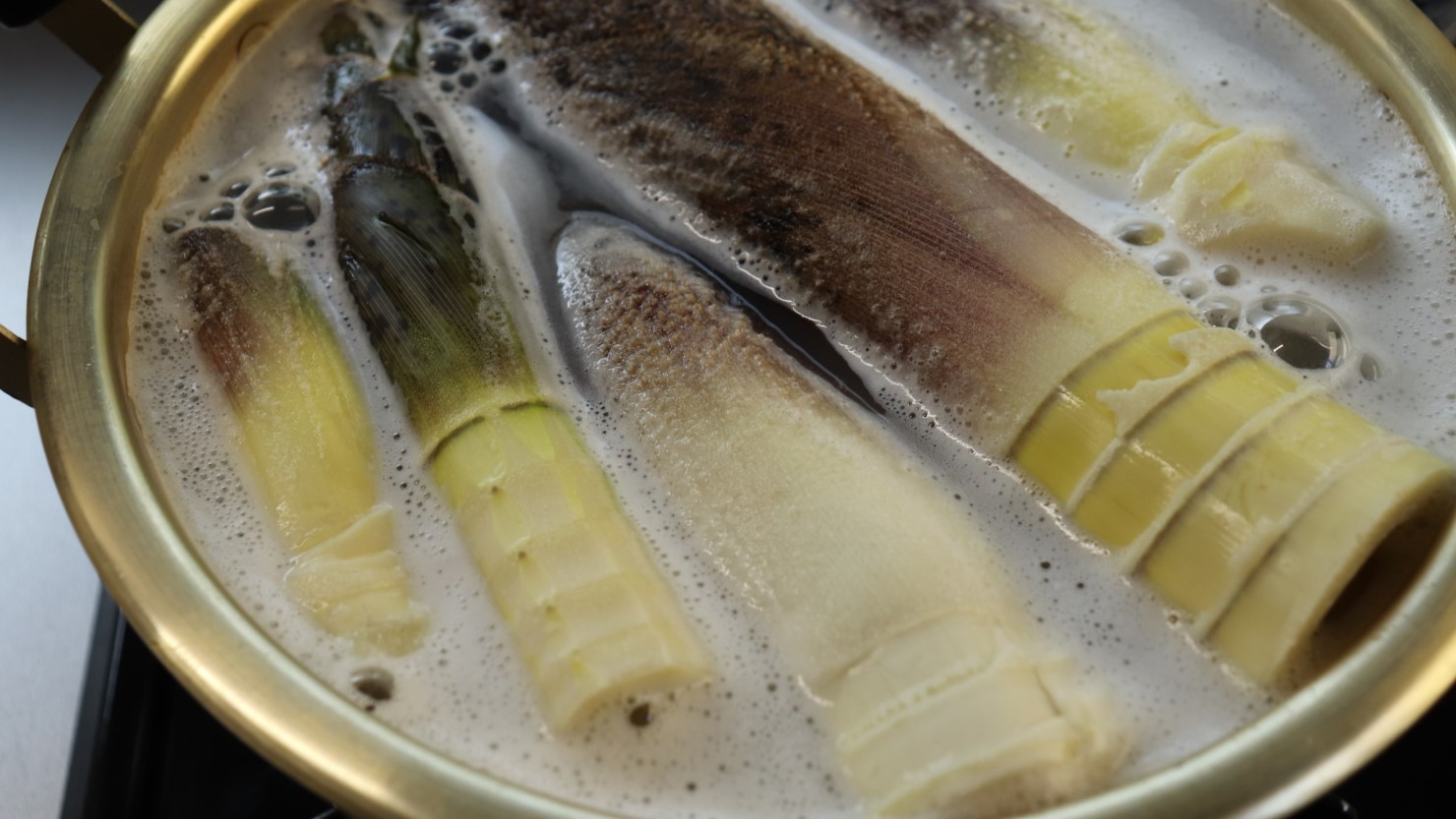 米のとぎ汁が入った鍋でタケノコを茹でていく