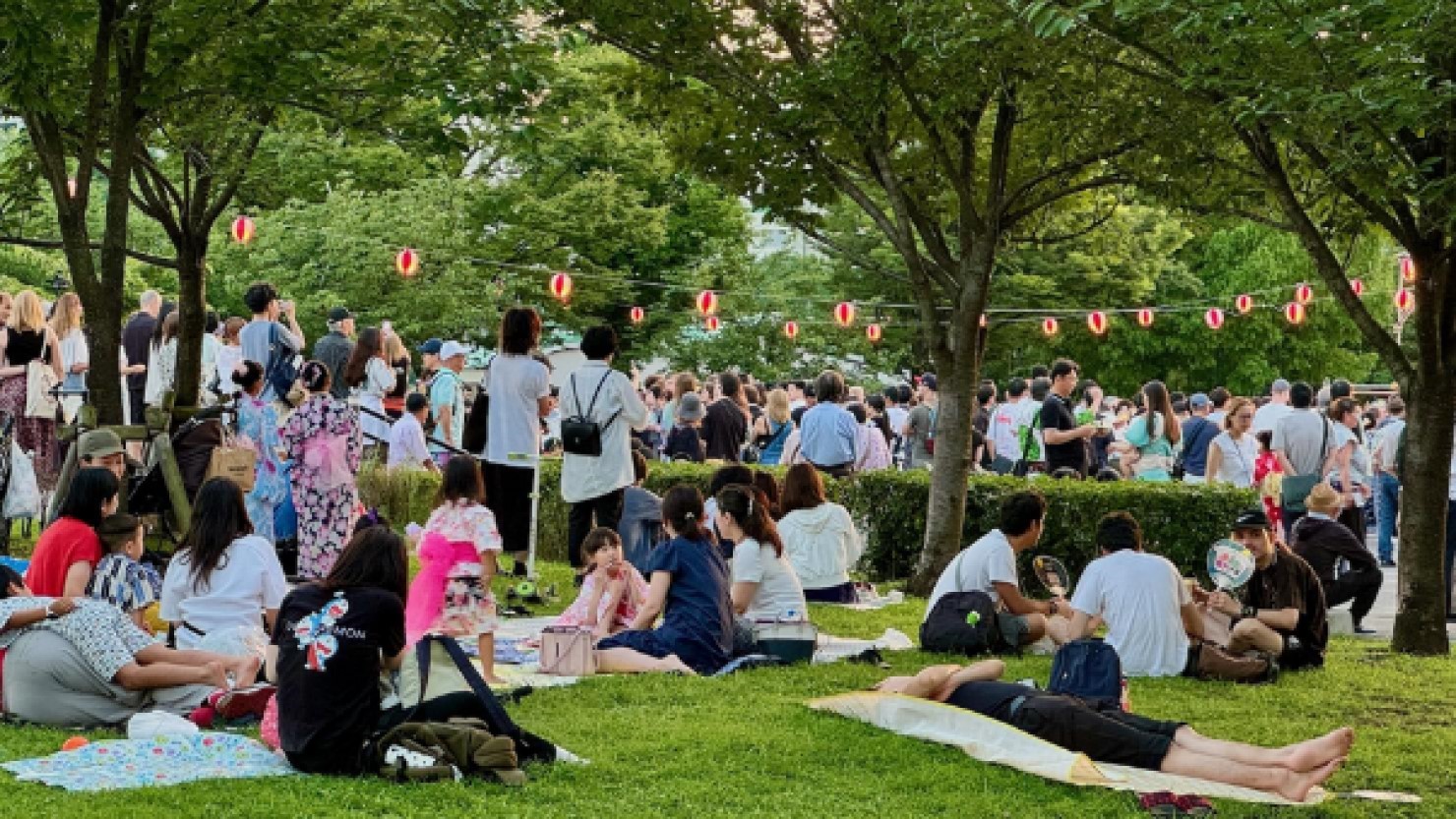 芝生が敷かれた桜の木の下で祭りを楽しむ地元の人々　©　鈴木博美