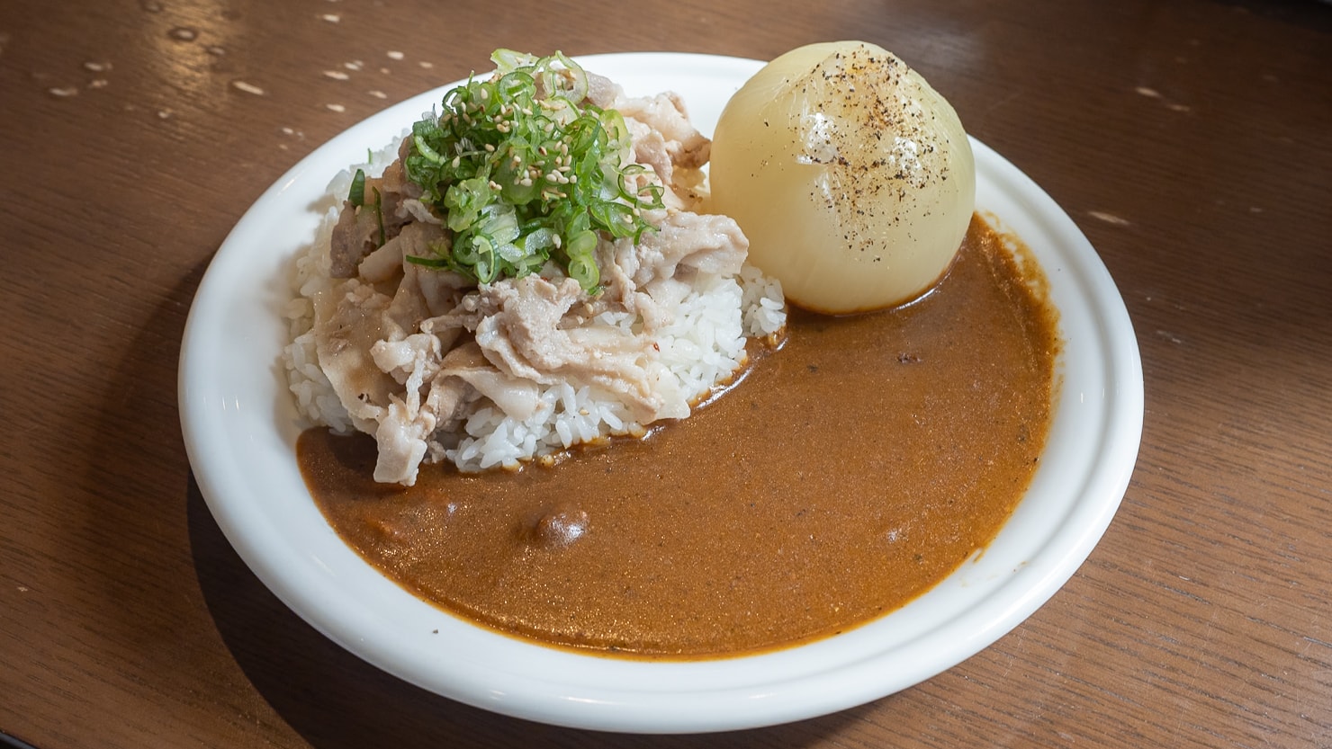 人気店Komi'zは、淡路島産の玉ねぎが丸々1個添えられた「丸ごと玉ねぎカレー」が看板メニュー。見た目のインパクトもさることながら、玉ねぎはトロトロで柔らかく甘味が強いのが特徴（写真はさらに「豚ねぎ塩」も追加トッピング）