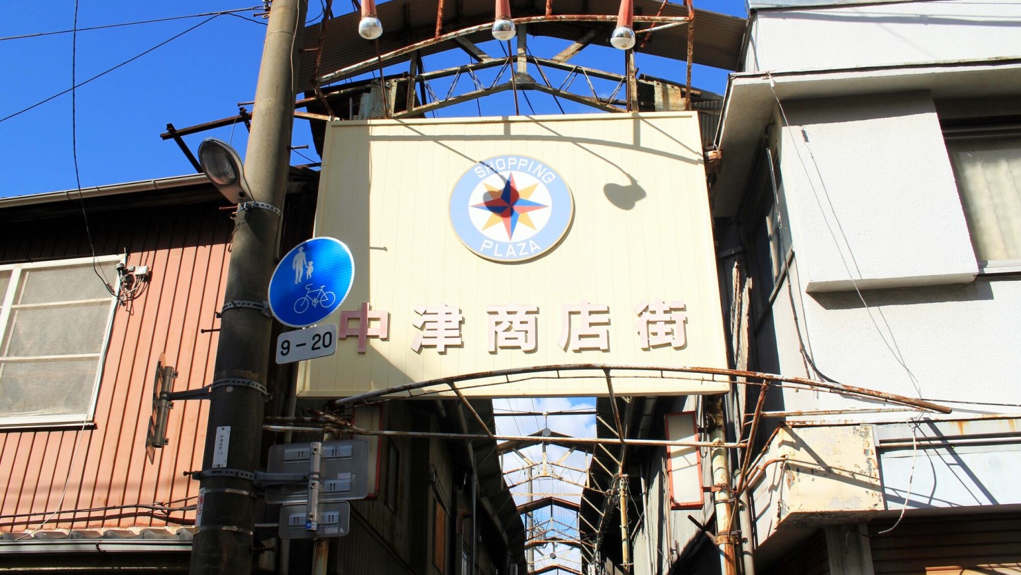 中津商店街の入り口看板。アーケードが取られて太陽光が差し込む
