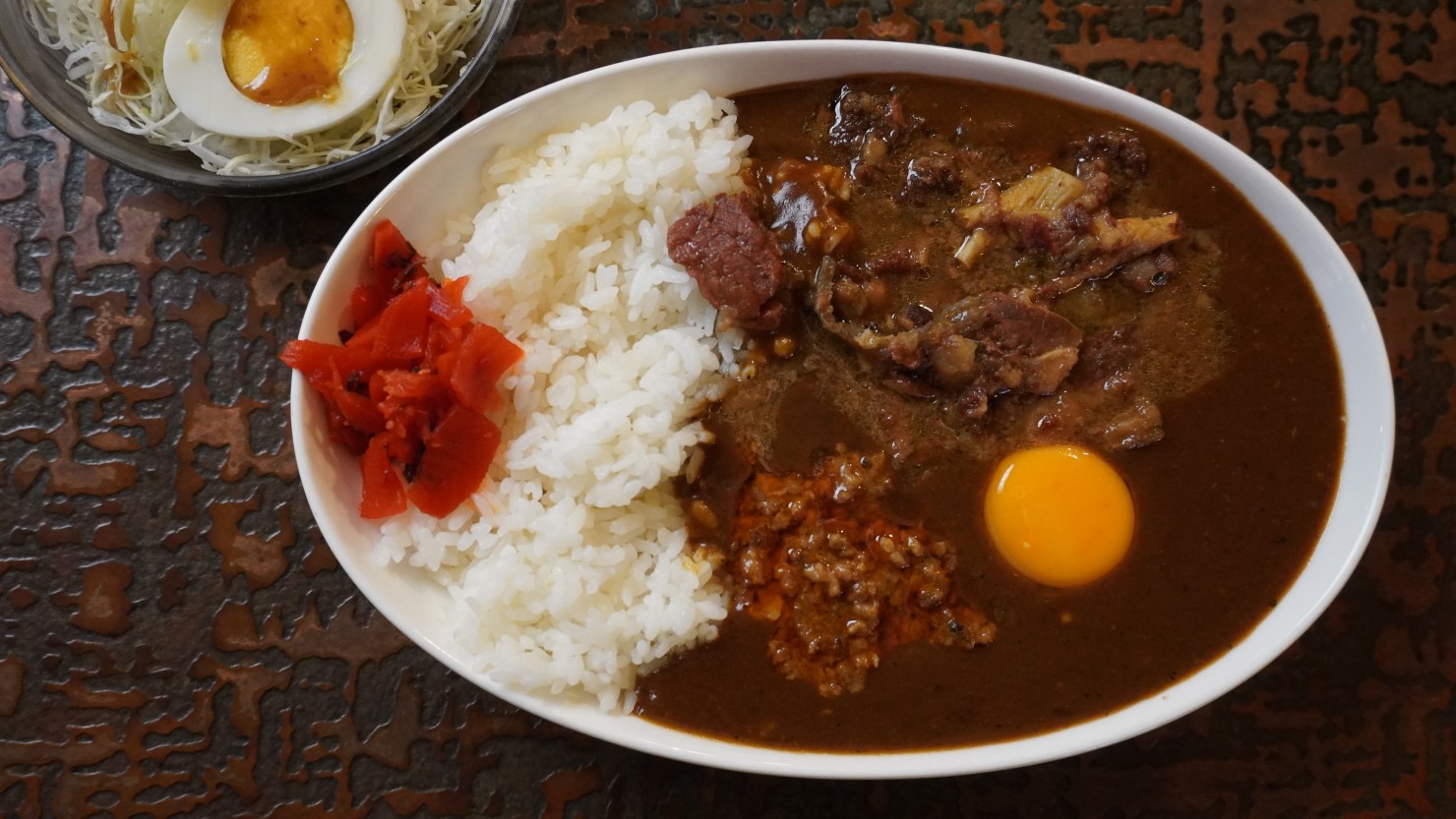 ひき肉のスタミナカレーは、トッピングの具材に合わせて、1号から５号までラインアップ。写真は、カレーの中でも最も人気の５号（牛すじ）カレー、サラダが付いてなんと800 円！