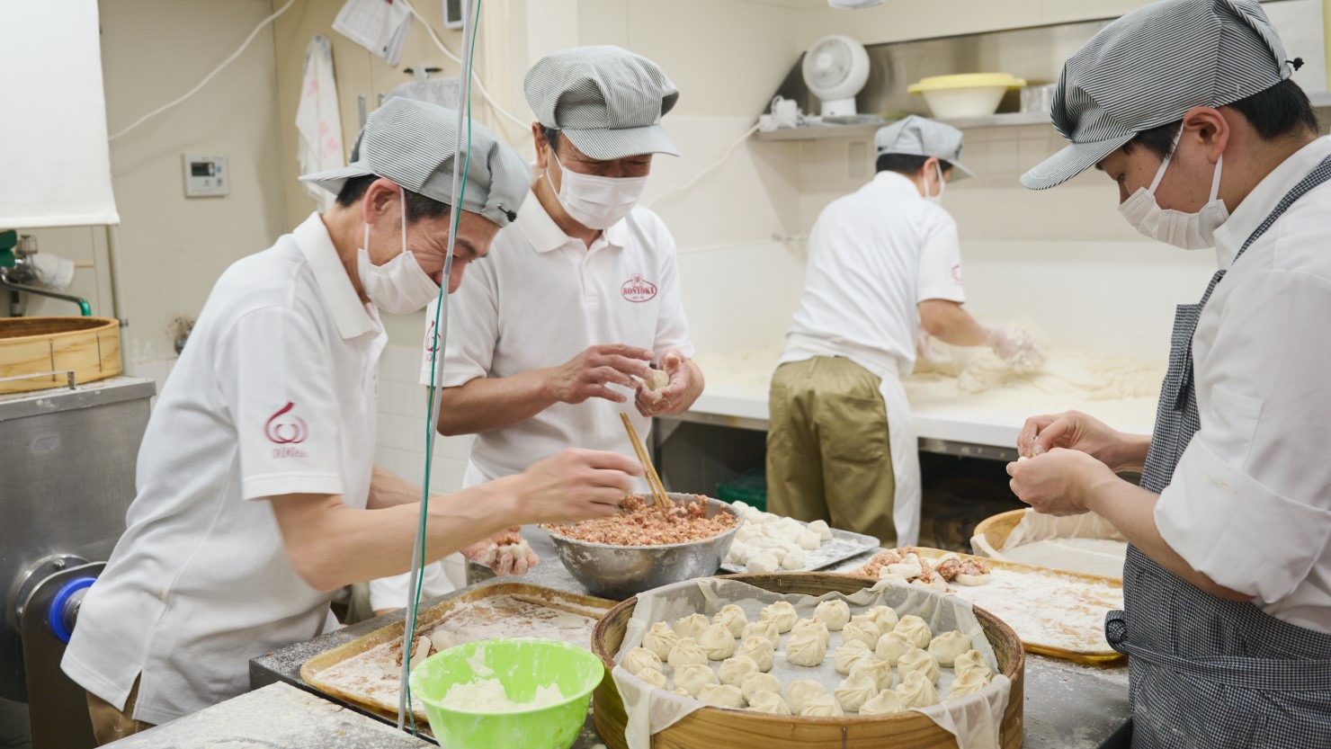 職人たちが豚まんを手際よく包む風景
