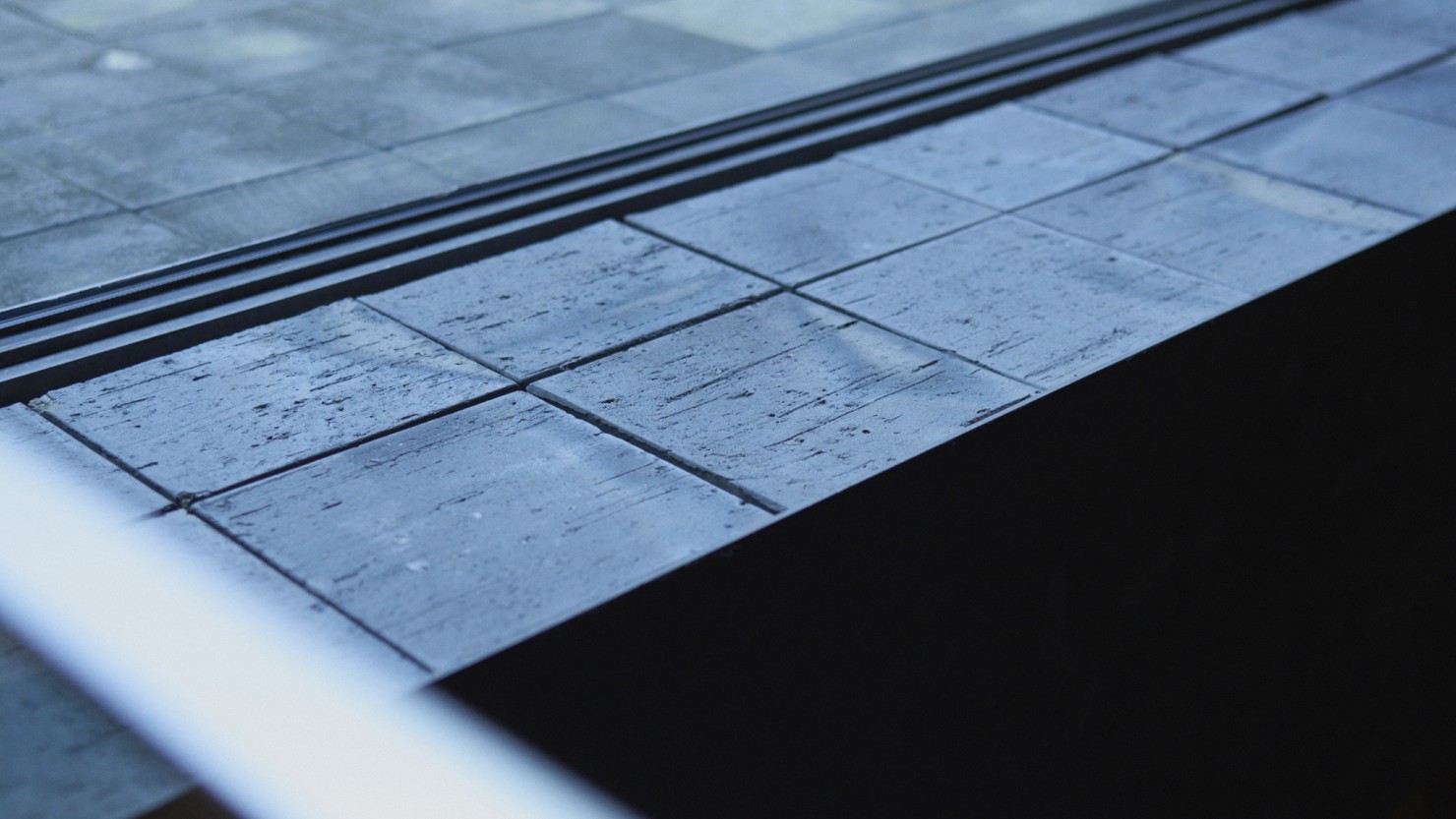 中庭にある敷き瓦は、色むらや大きさ、形も不ぞろい。現代では工場で大量に焼かれる瓦を、あえて昔ながらの窯で焼き上げ、素材の表情が時とともに変化する様子を楽しむ場所となっている