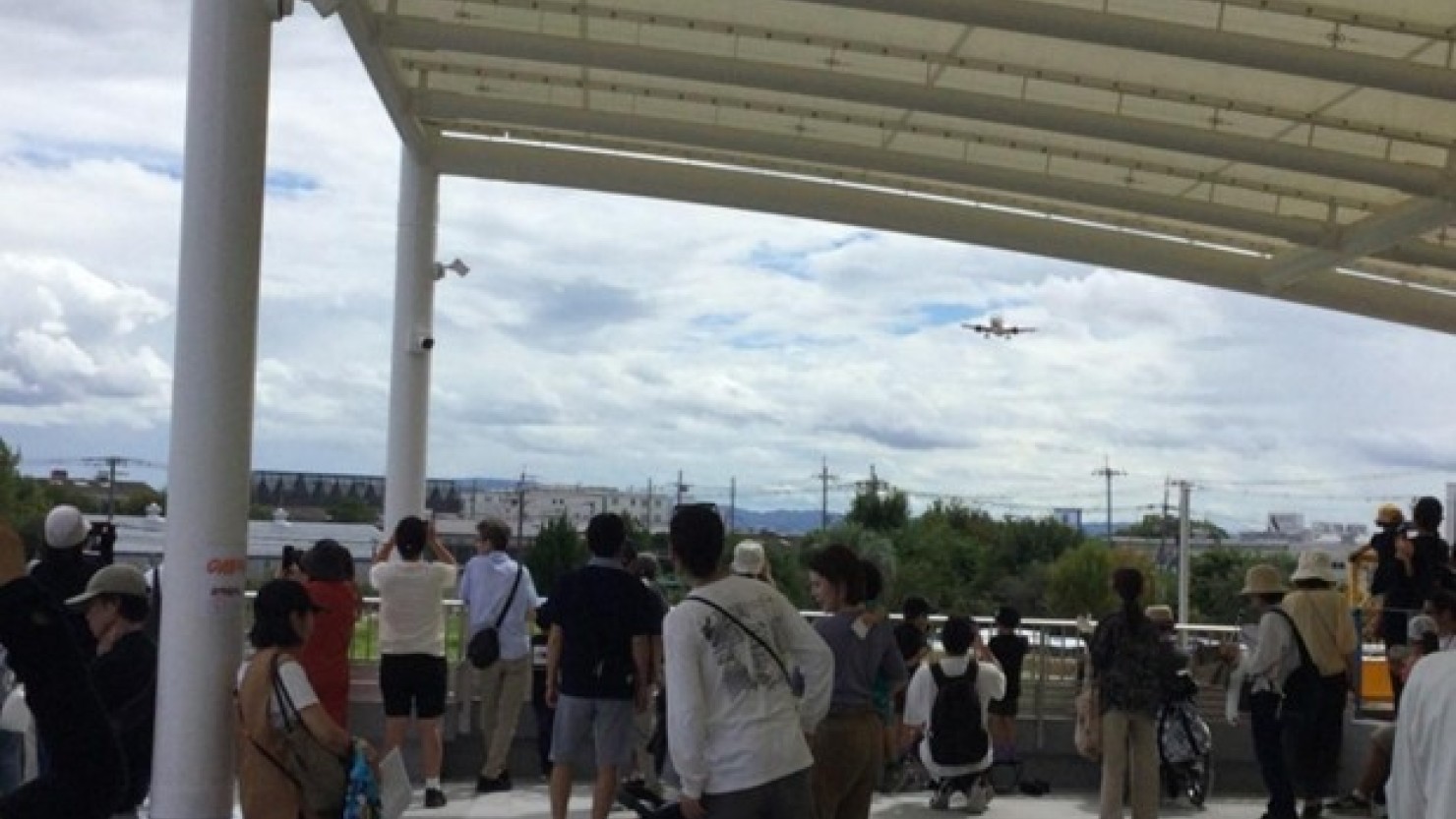 カメラを向ける人などにぎわう屋根付展望広場のデッキ