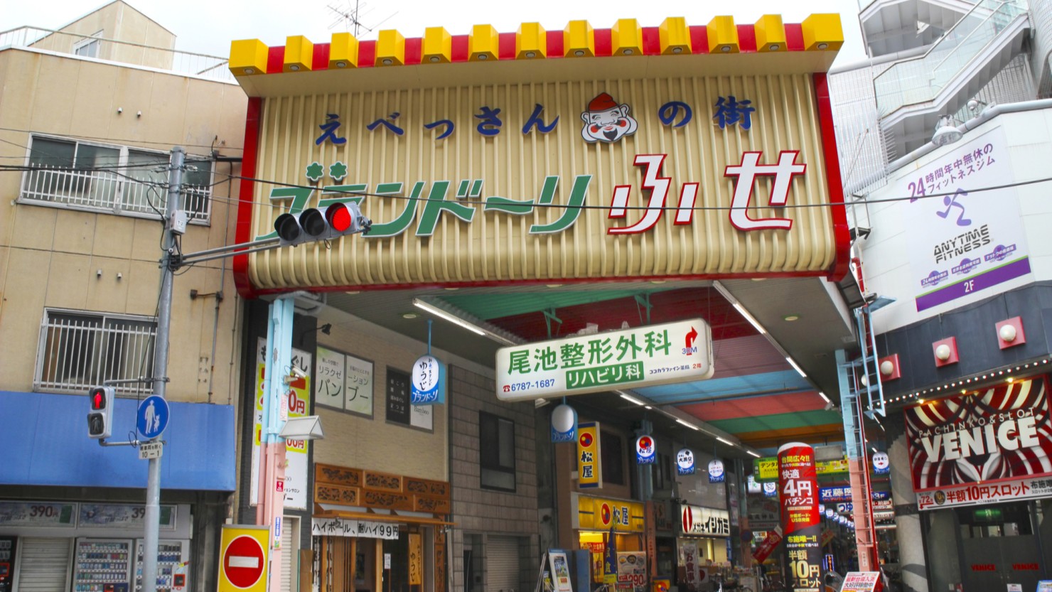 布施本町商店街の一角。居酒屋にピザ屋、スパイス屋、ラーメン屋とバラエティ豊富。回転寿司のシステムを発明した「元禄寿司」の本店もある。