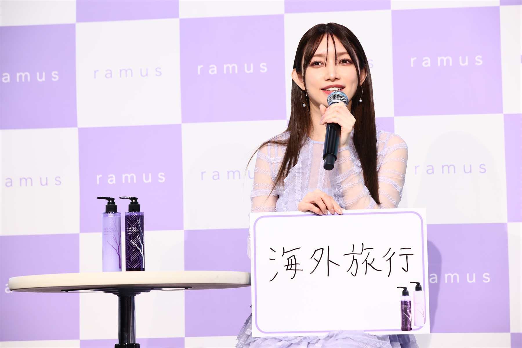 後藤真希さんプロデュース「ramus」のシャンプー＆コンディショナーの横でフリップを持ち質問に答える後藤真希さん