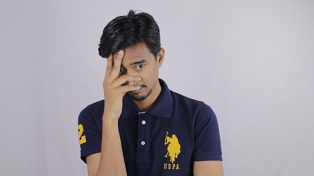 手を顔に当てて困っている男性