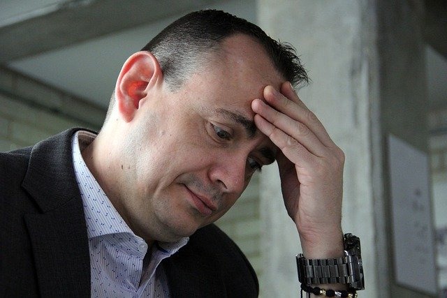 交通事故による頭痛で頭を押さえている男性