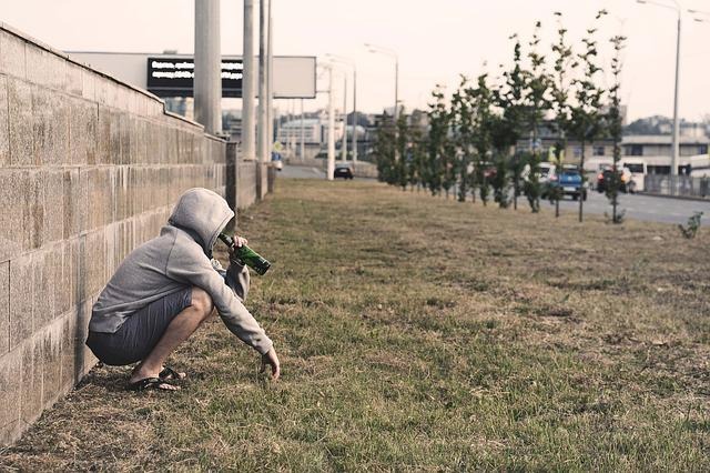 しゃがみこんでコーラを飲む男性