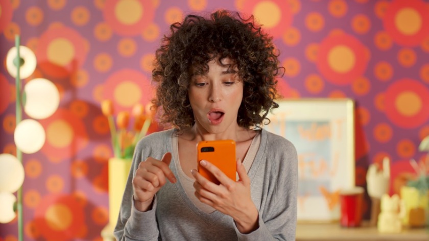 スマホを手におどろいた顔をしている女性の写真