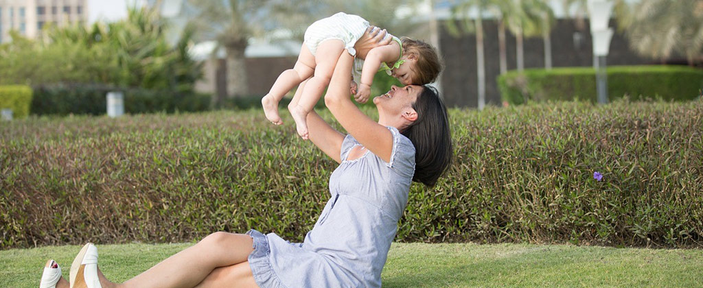 芝生の上で赤ちゃんを抱きあげる女性