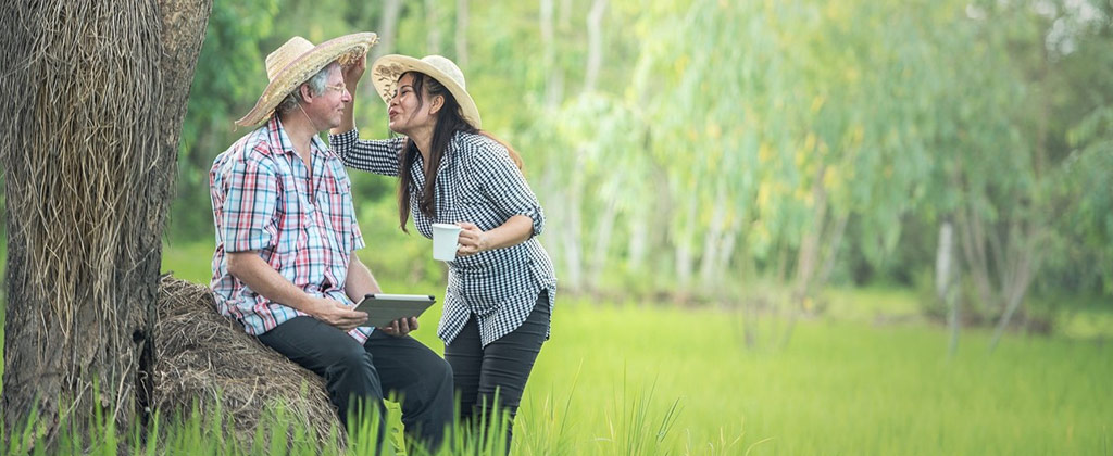 草原の中で麦わら帽子をかぶる夫婦