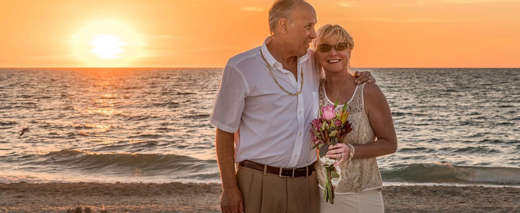 海辺の夕日と花を持った夫婦