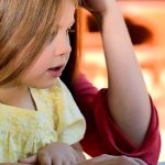 女性の膝の上でパソコンを触る女の子