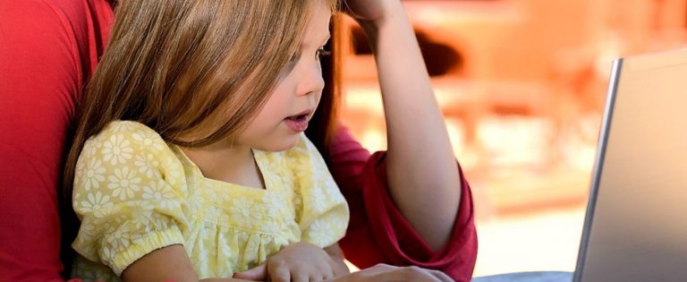 女性の膝の上でパソコンを触る女の子