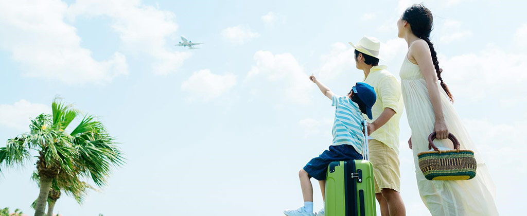 リゾート地で空を飛ぶ飛行機を眺める家族