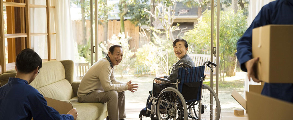 車いすに乗った女性と段ボールに荷物をつめる家族