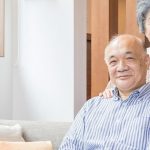 座っている男性と肩に手を添える女性