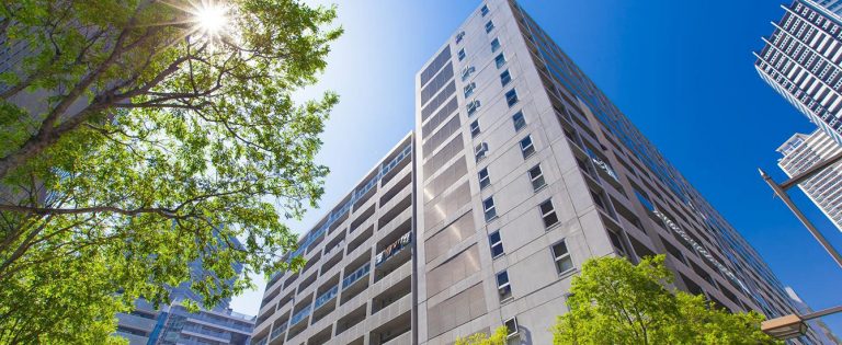 青空の中建つマンションと木