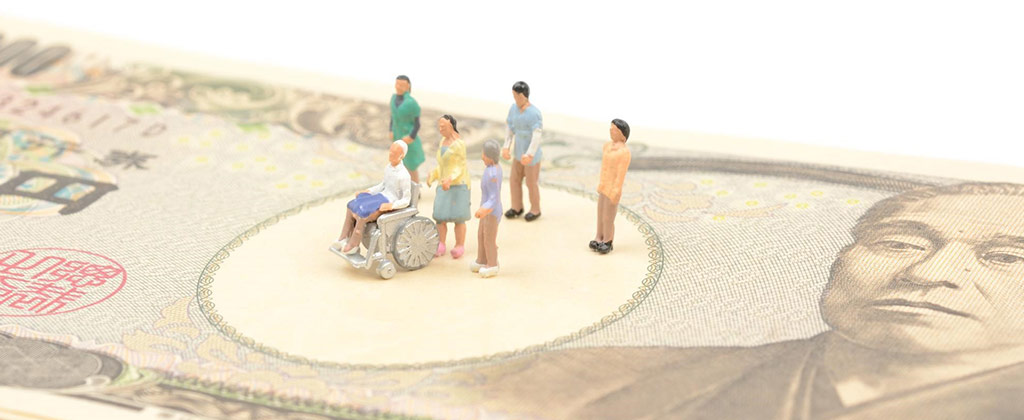 一万円札の上にのっている家族のミニチュア