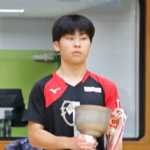 キャプテンの男子選手の写真。東海大会の優勝トロフィーを持っています。