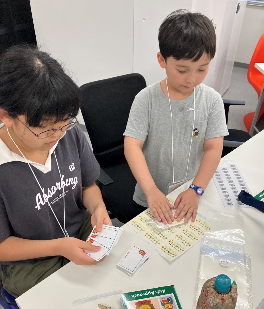 子どもたちが梱包作業をお手伝いする様子の写真