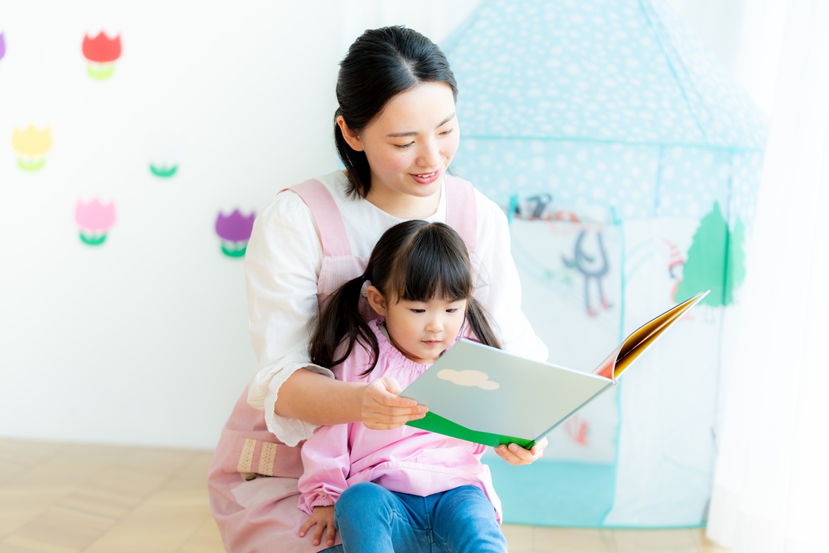 絵本を読む保育士と子供