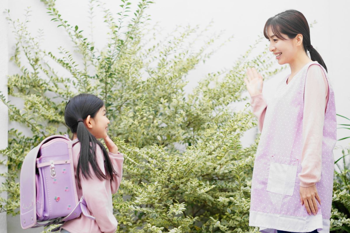 子どもを見送る保育士