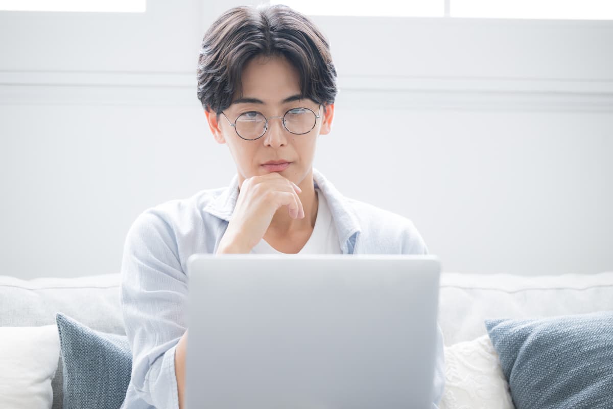 パソコン画面を見ながら考え事をする男性