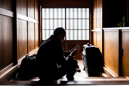 旅館の玄関先に座り込む男性