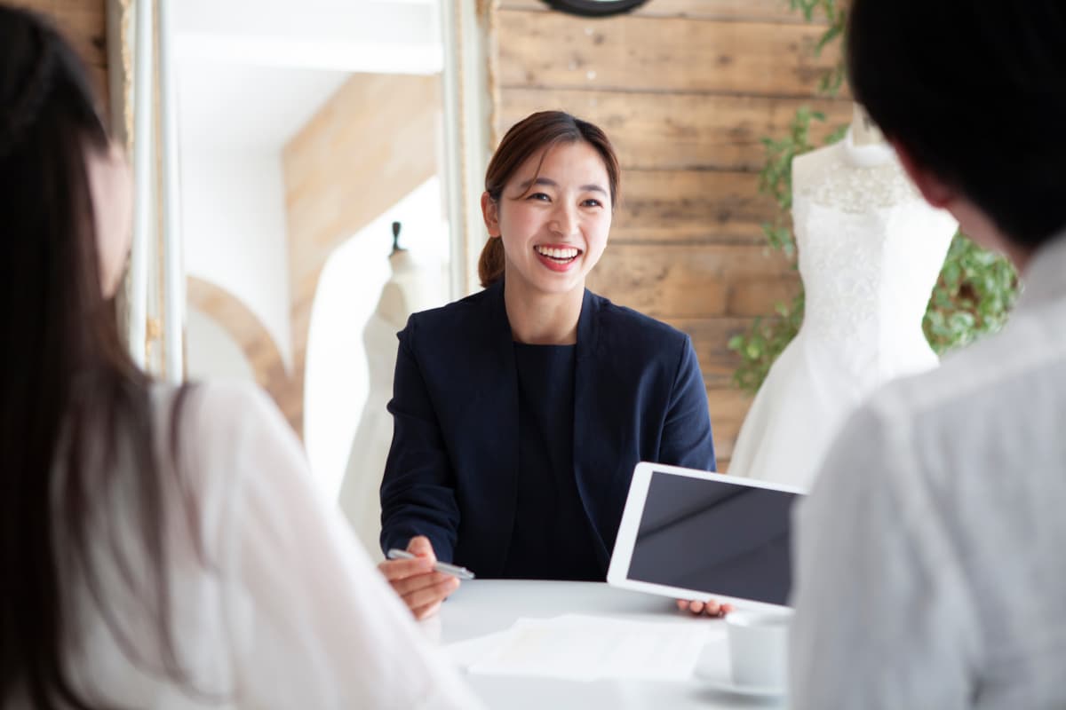 新郎新婦と結婚式の打ち合わせをするプランナー