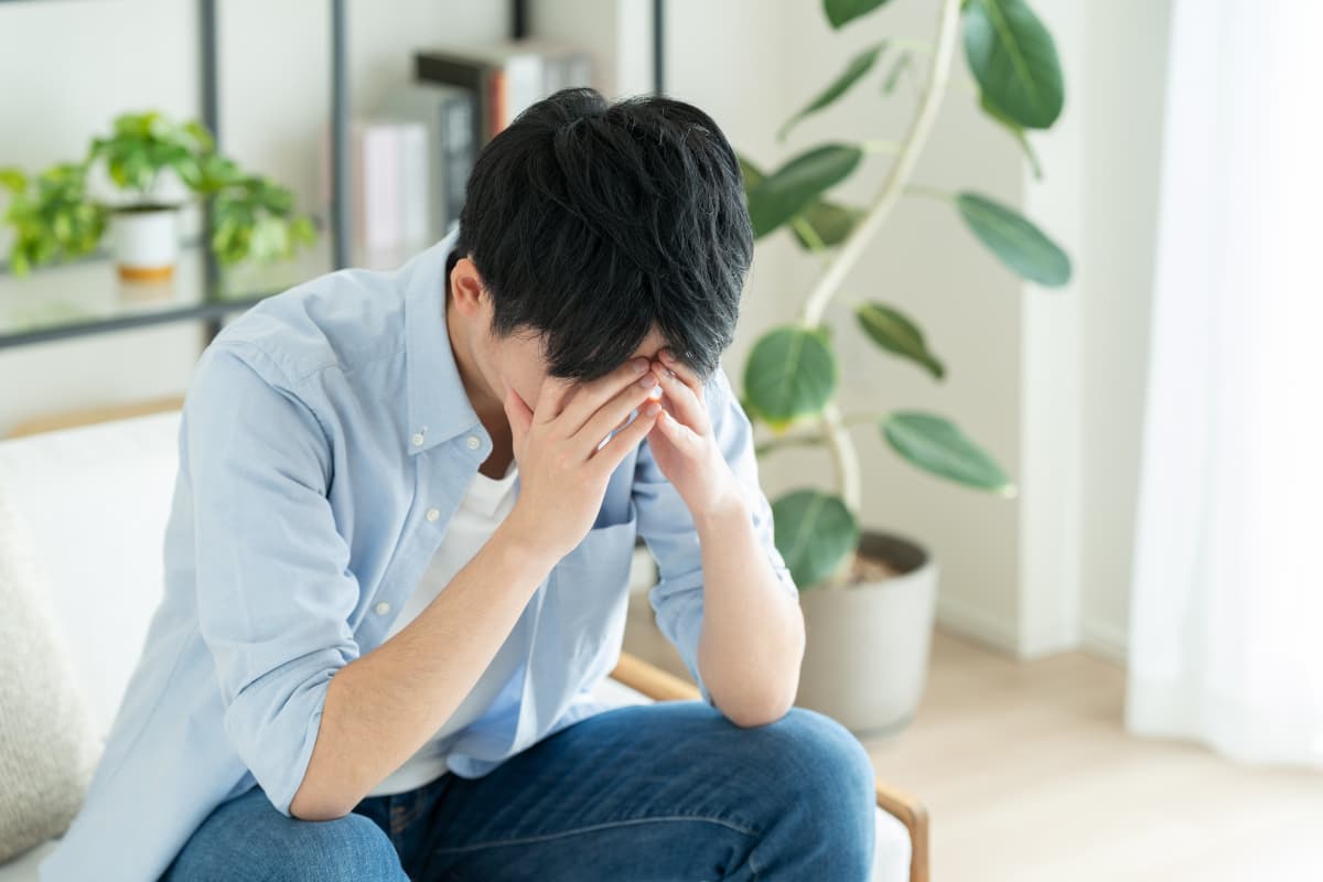 ソファーに座って頭を抱える男性