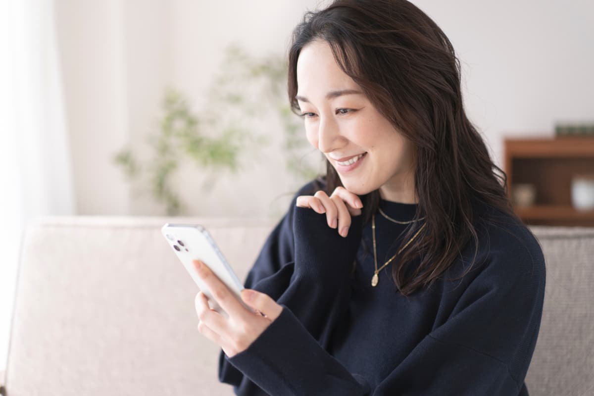 スマホを見てほほえむ40代女性