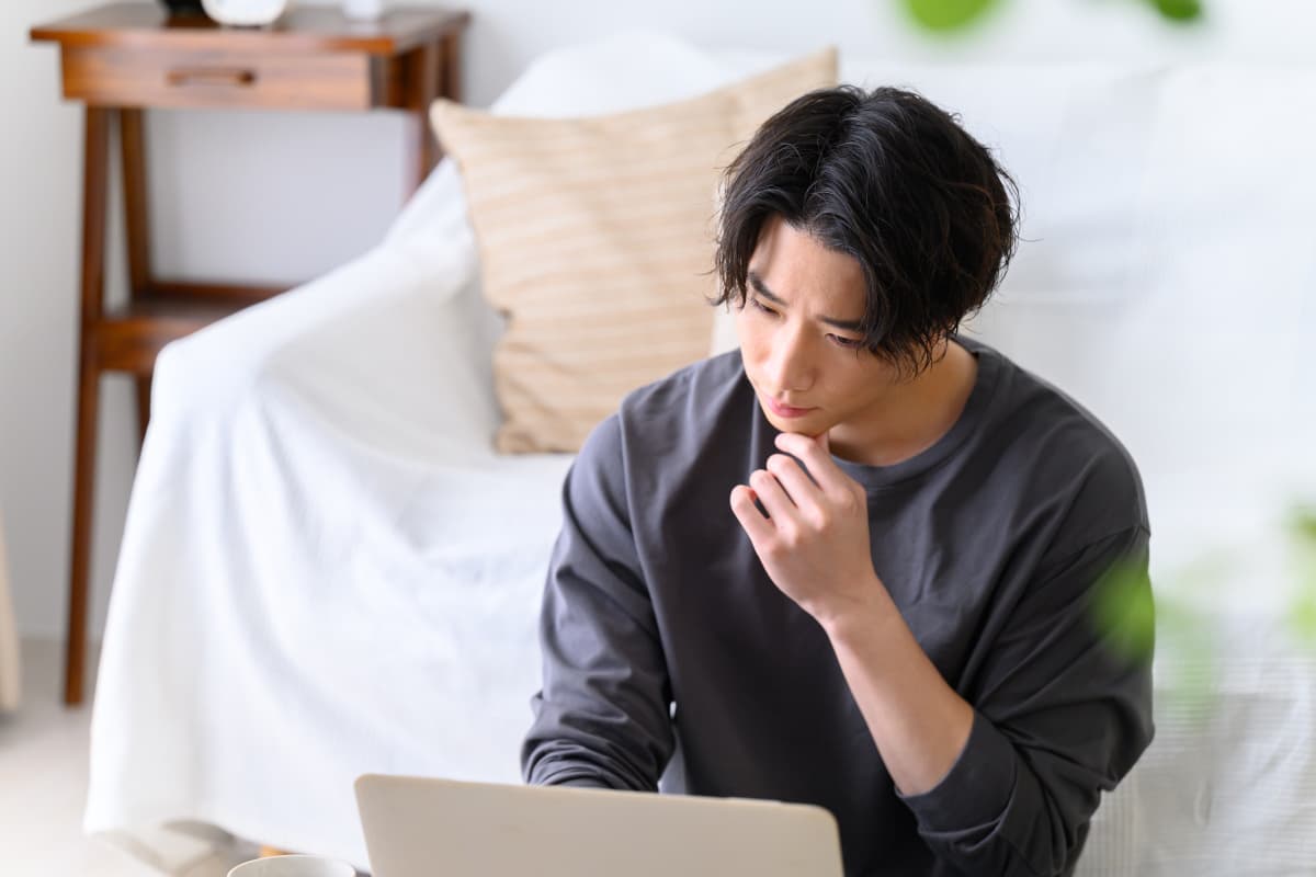 パソコン画面を見ながら考え事をする男性