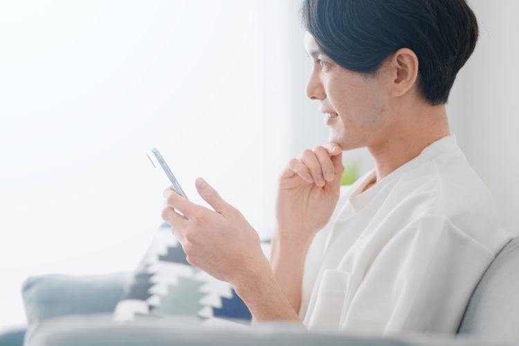 スマホを見て悩む男性