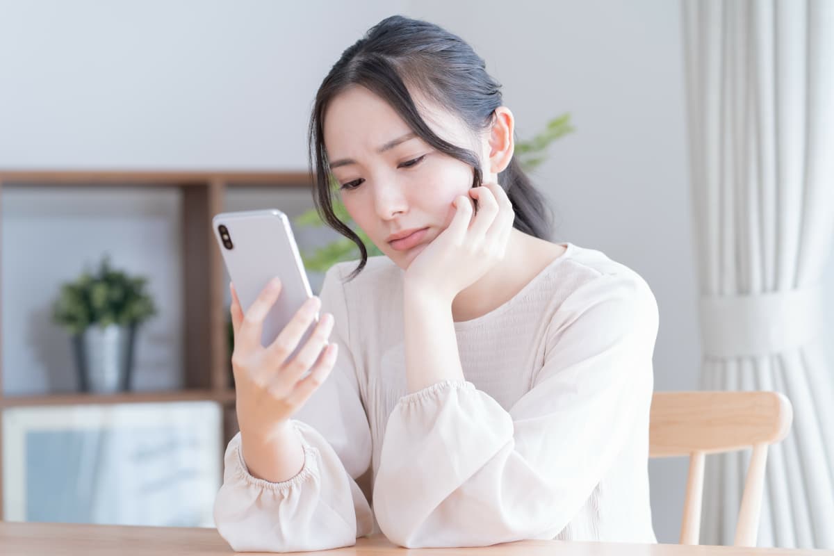 スマホを見ながら考え事をする女性