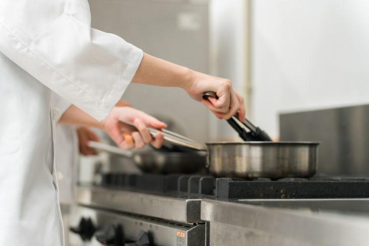 ガスコンロの上で料理をする調理師