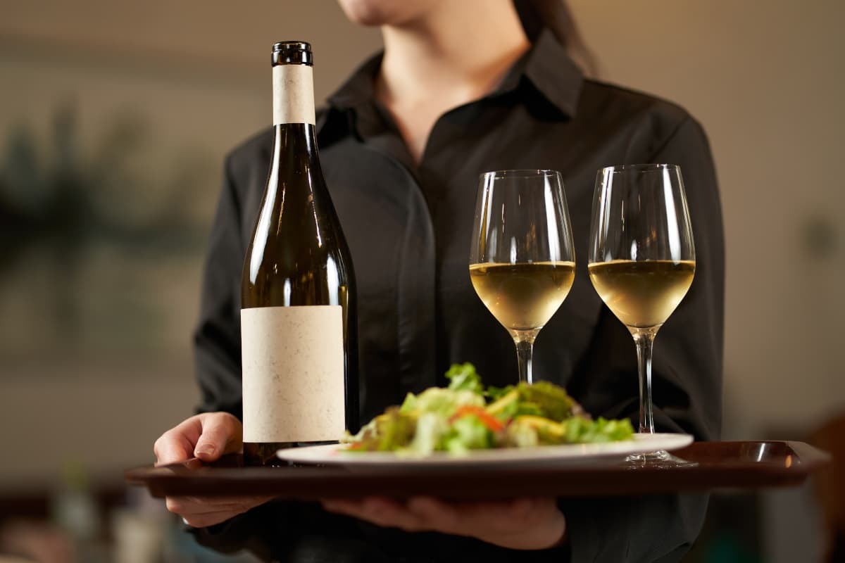 お客様にワインとサラダを運ぶ女性スタッフ